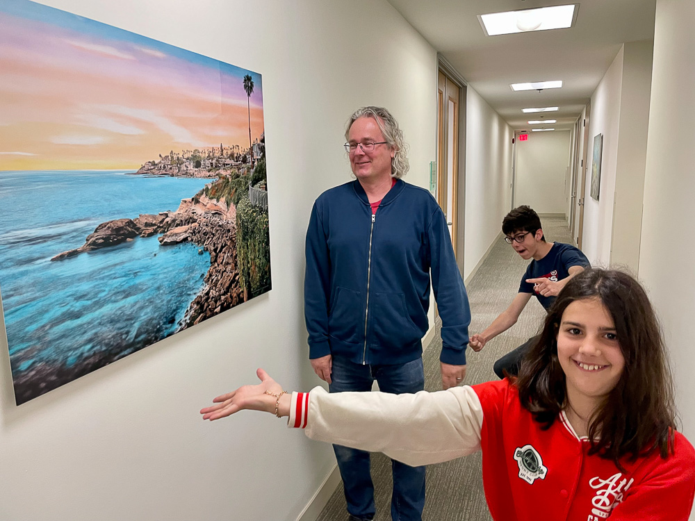 Roy and two children looking at 30x40 Welcome to Bird Rock II on metal in hallway